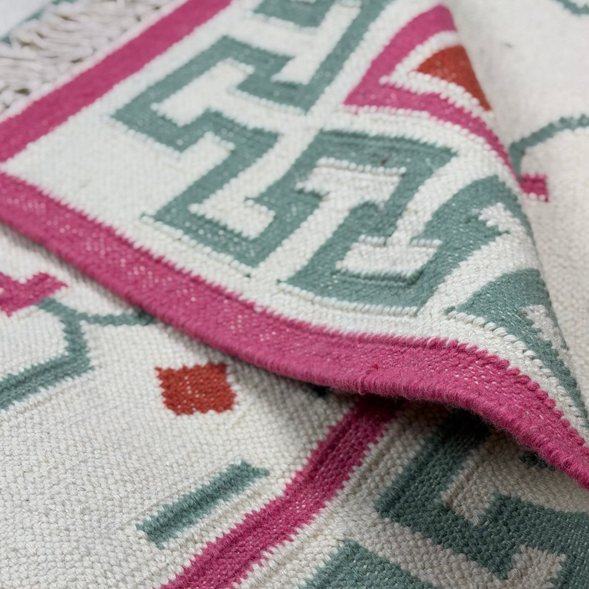 Close-up of a patterned rug with pink and green geometric design