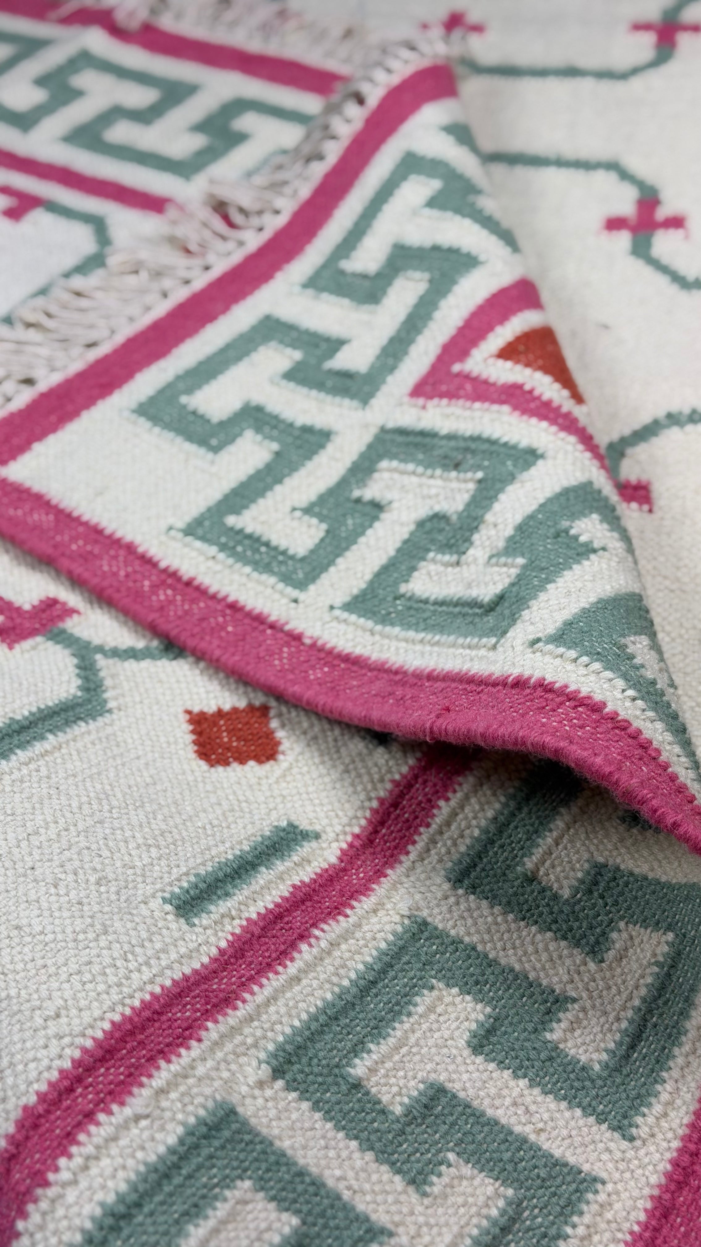 Close-up of a patterned rug with pink and green geometric design