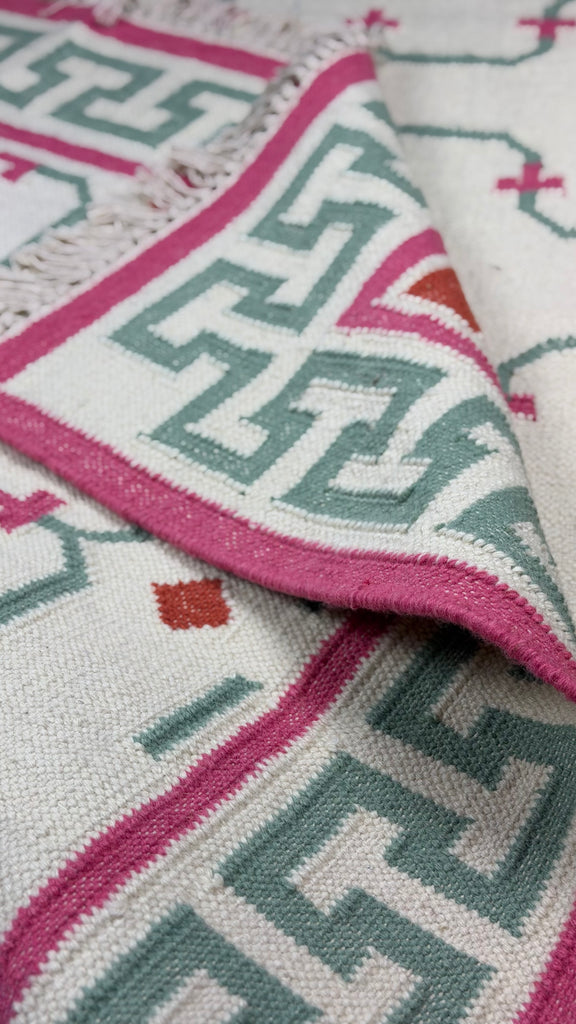 Close-up of a patterned rug with pink and green geometric design