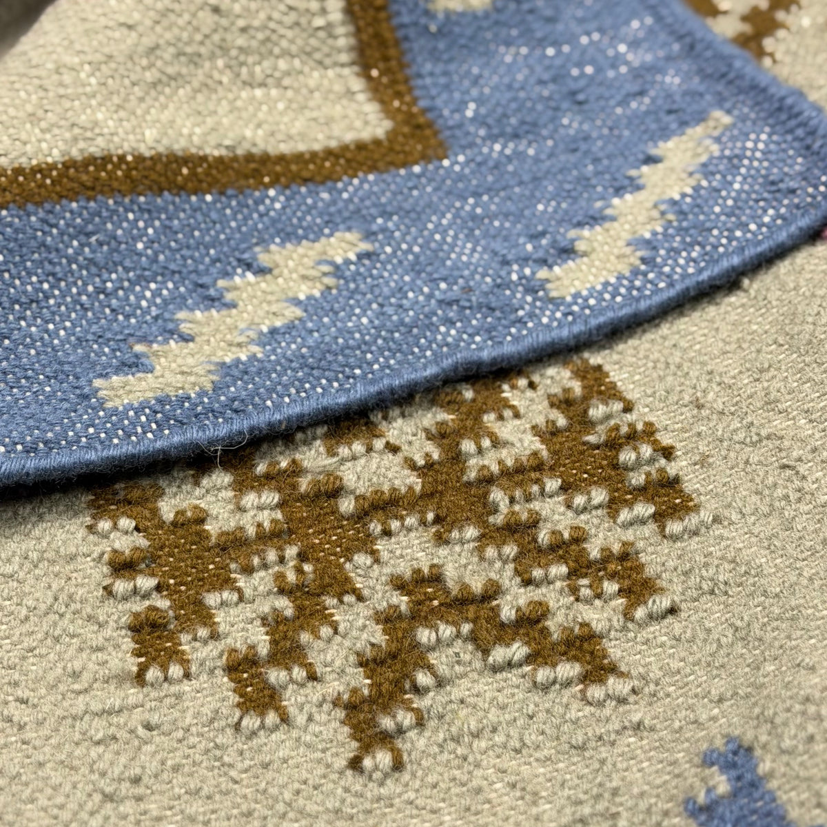 Close-up of the rug with pattern in blue, brown, and grey.