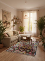 Cozy living room with a colorful rug, plants, and a window with white curtains.