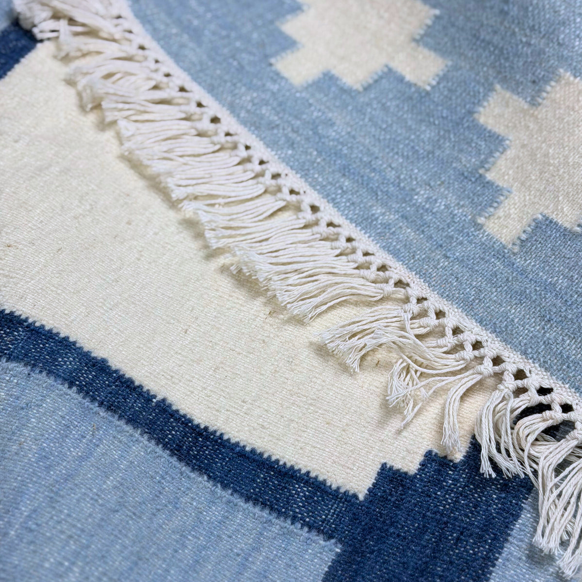 Close-up of a blue and white patterned rug with fringed edge