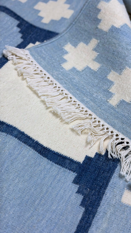 Close-up of a blue and white patterned rug with fringed edge