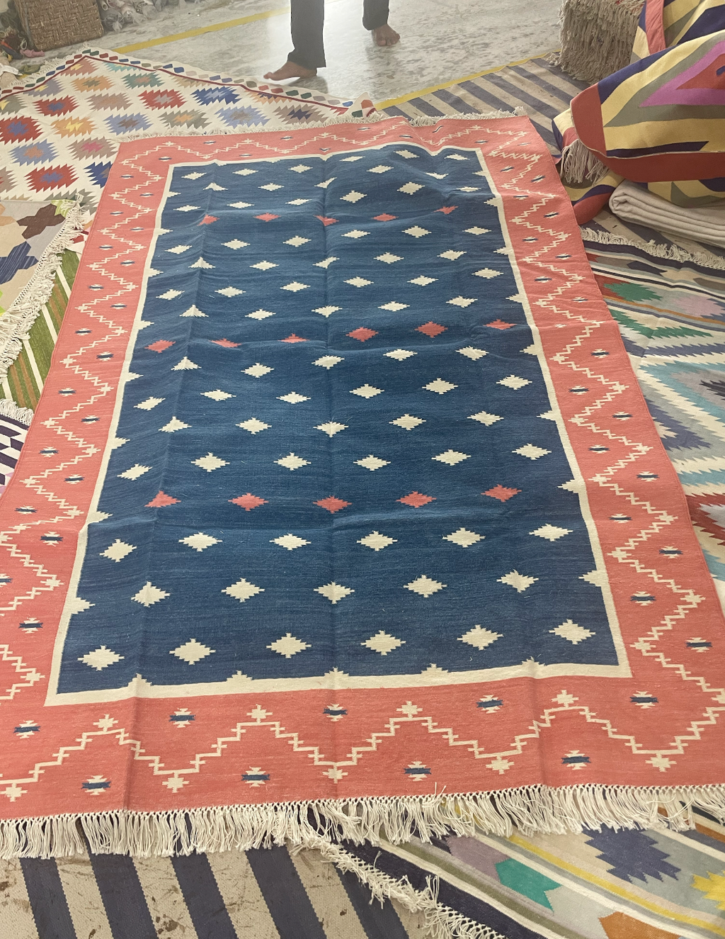 Geometric patterned rug with blue and pink colors on a floor.