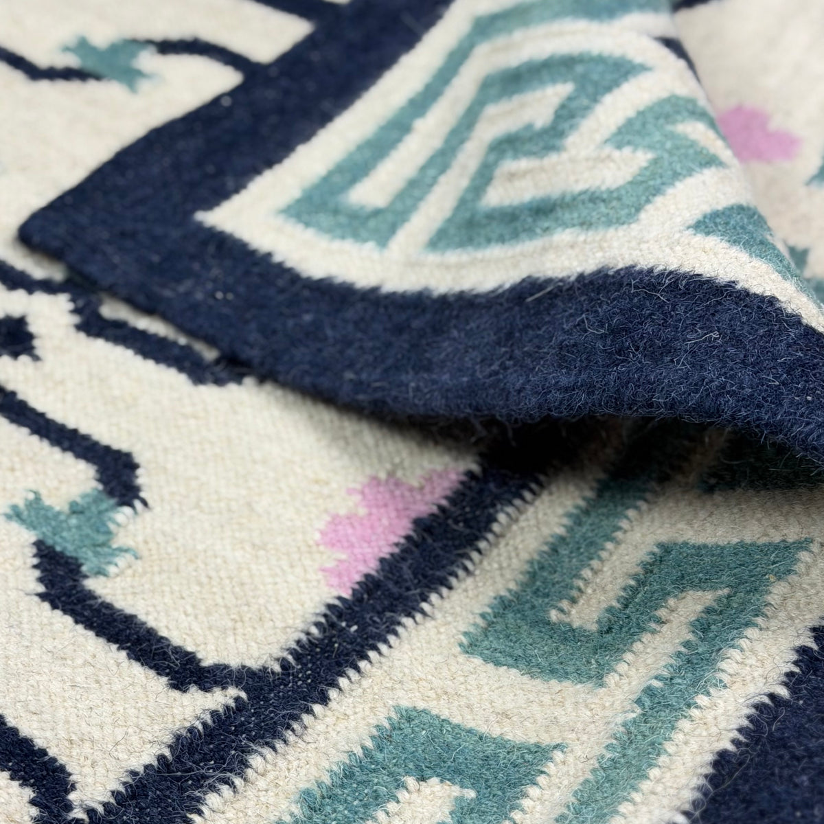 Close-up of a patterned rug with geometric designs in blue, white, and black.