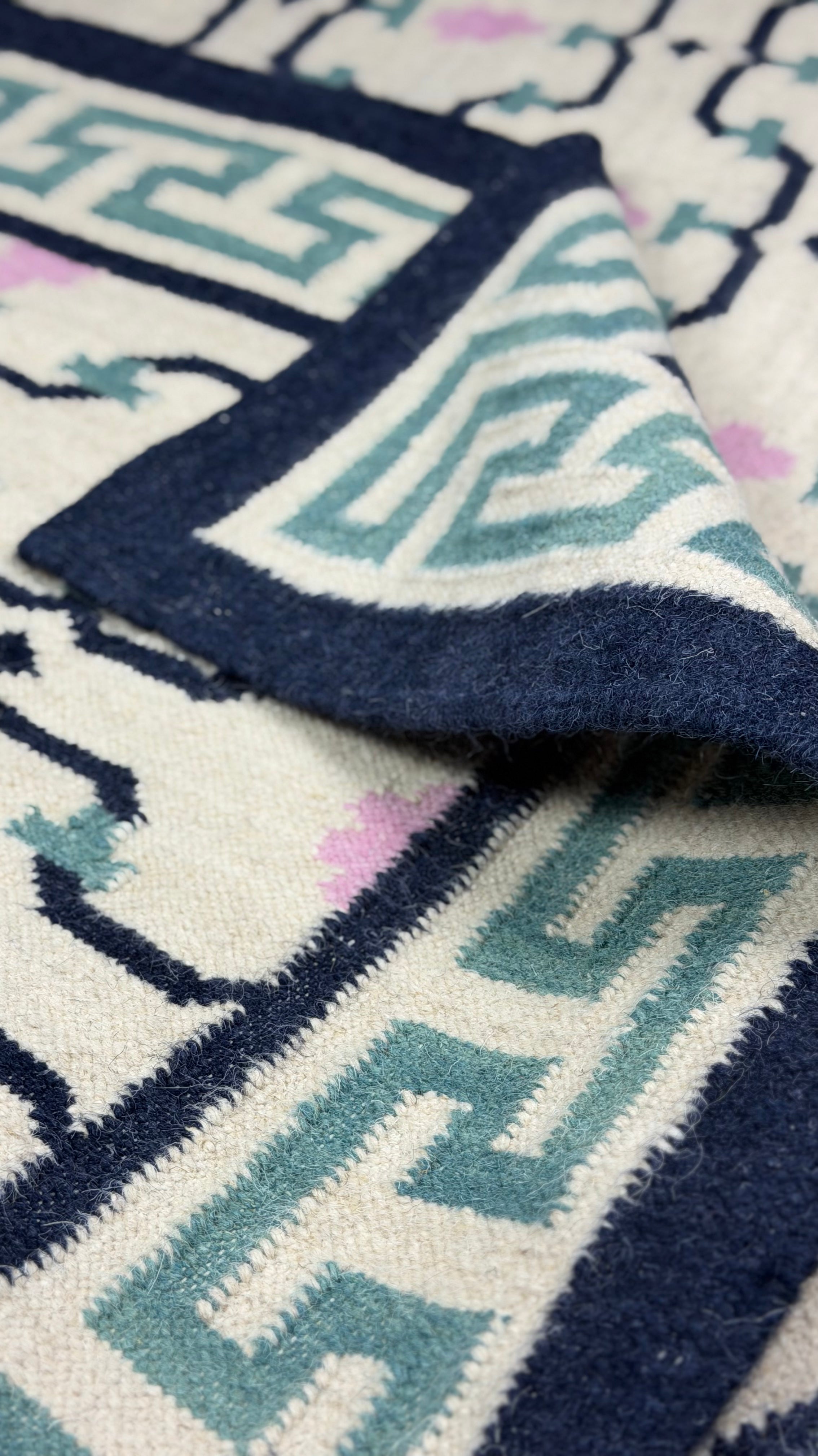 Close-up of a patterned rug with geometric designs in blue, white, and black.