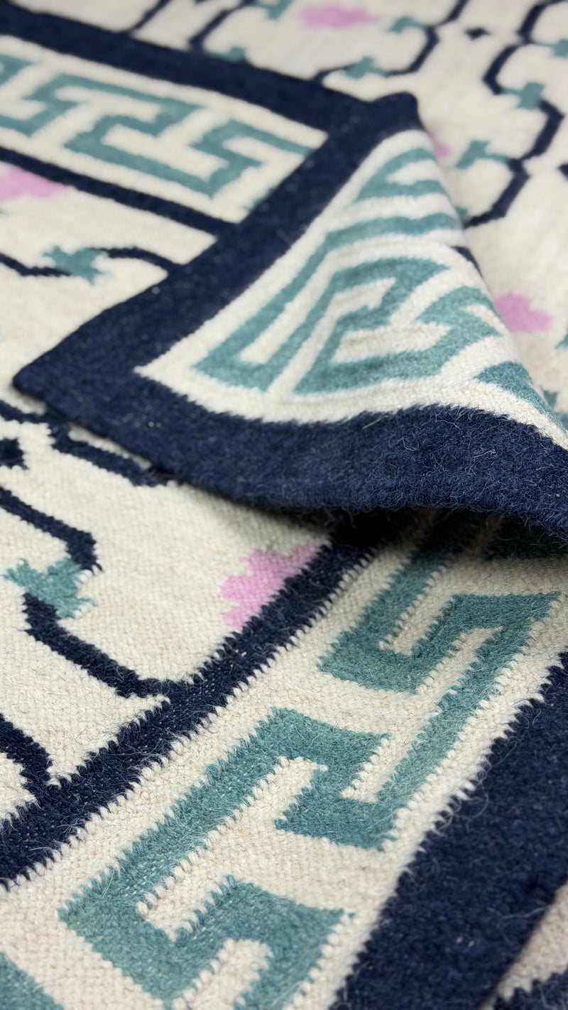 Close-up of a patterned rug with geometric designs in blue, white, and black.