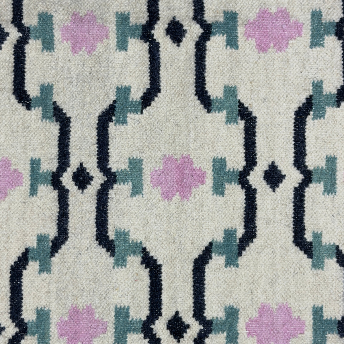 Patterned rug with geometric design featuring black, purple, and gray colors on a textured surface.