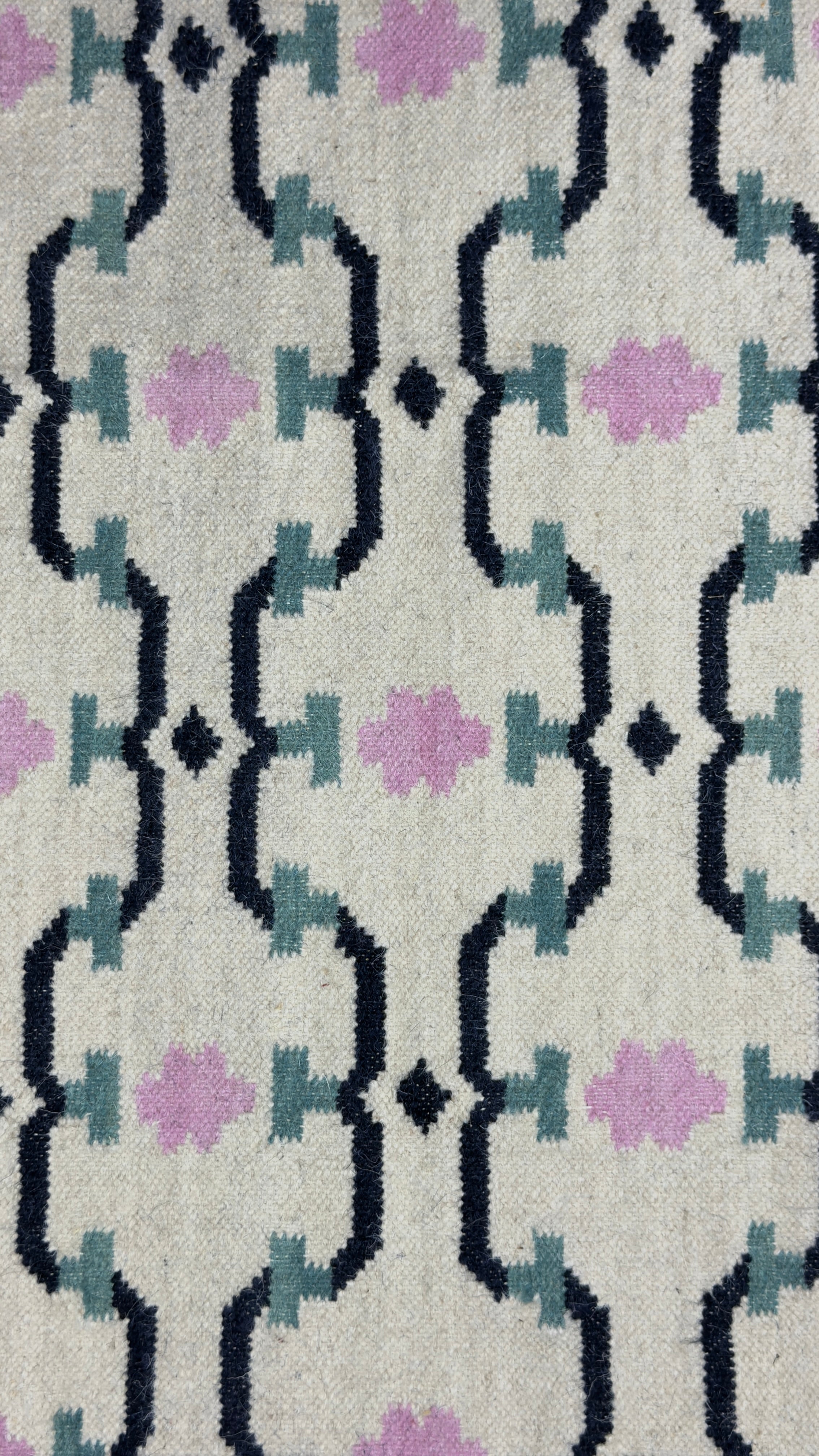 Patterned rug with geometric design featuring black, purple, and gray colors on a textured surface.