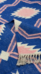 Close-up of a blue and pink patterned rug with tassels.