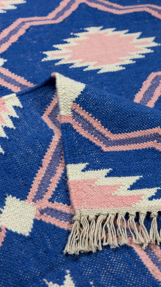 Close-up of a blue and pink patterned rug with tassels.